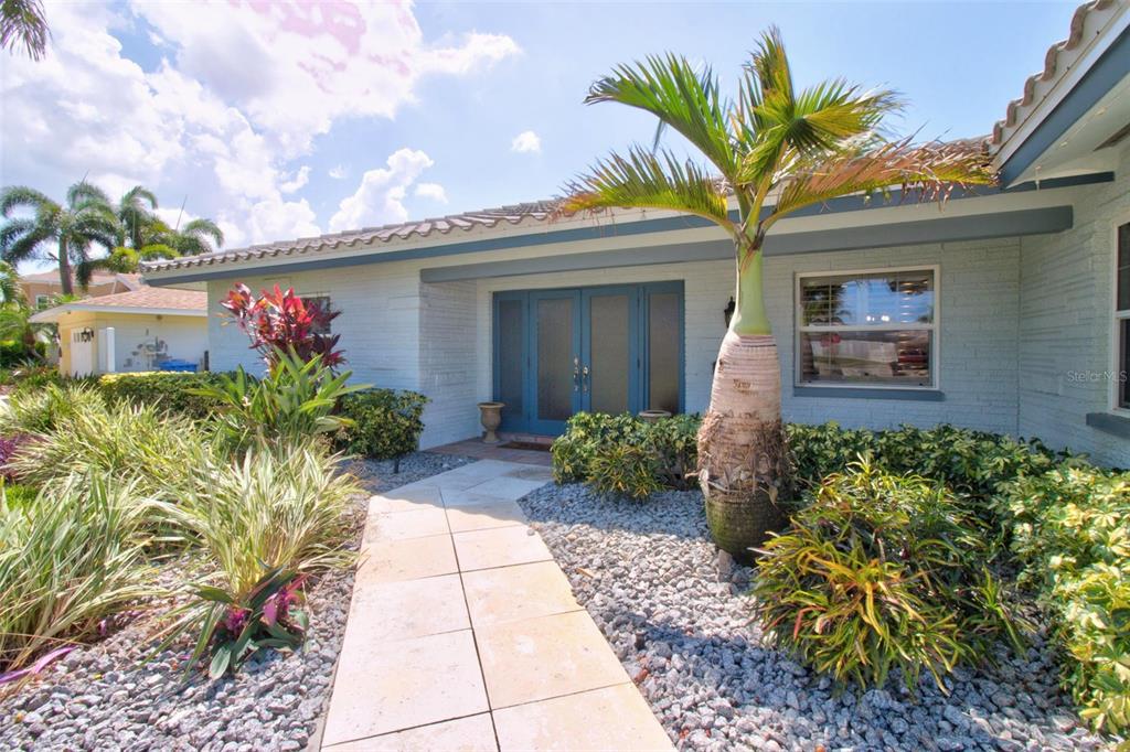 A light-colored brick house features a palm tree, a stone walkway, and double front doors — 8094 12TH AVENUE S, ST PETERSBURG, FL