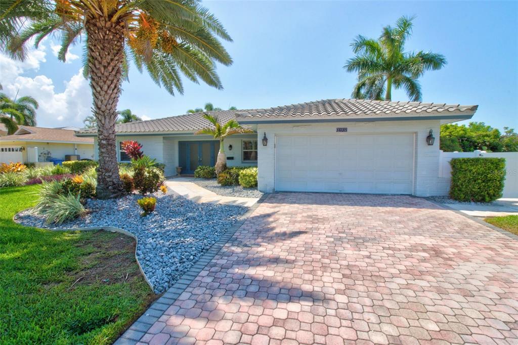 A single-story house with a white brick facade, a tiled roof, and a paved driveway — 8094 12TH AVENUE S, ST PETERSBURG, FL