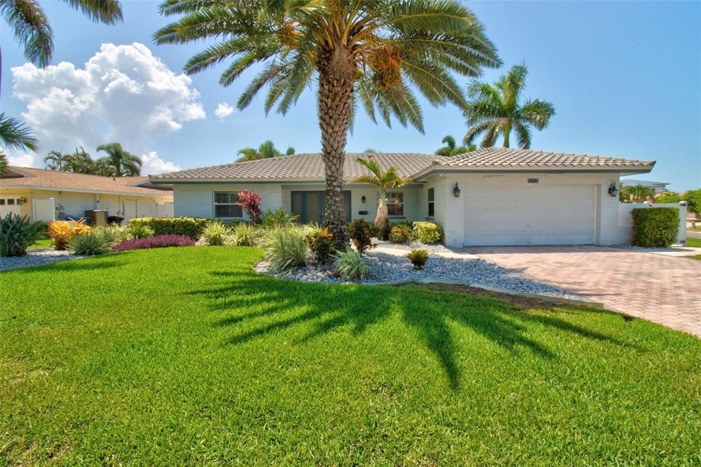 A single-story house with a white garage, tiled roof, and a large palm tree out front — 8094 12TH AVENUE S, ST PETERSBURG, FL