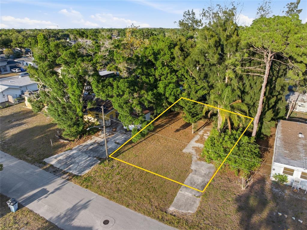 An aerial view shows a vacant, rectangular residential lot outlined in yellow next to trees — 61ST LANE, PINELLAS PARK, FL