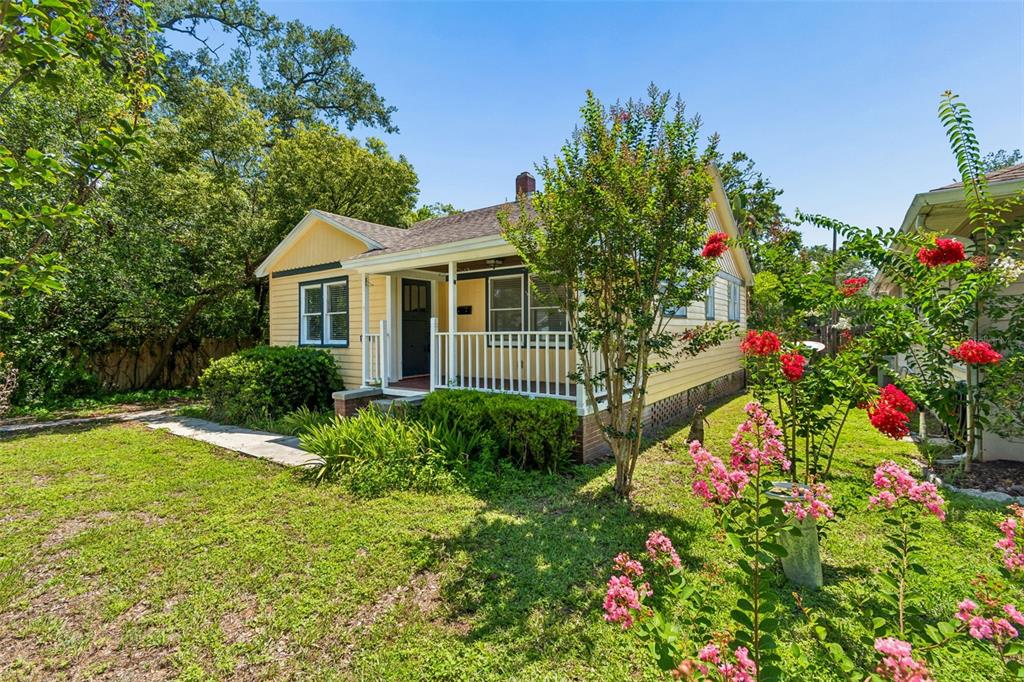 A yellow, single-story house with a front porch sits on a grassy, tree-lined lot — 1019 S TENNESSEE AVENUE, LAKELAND, FL