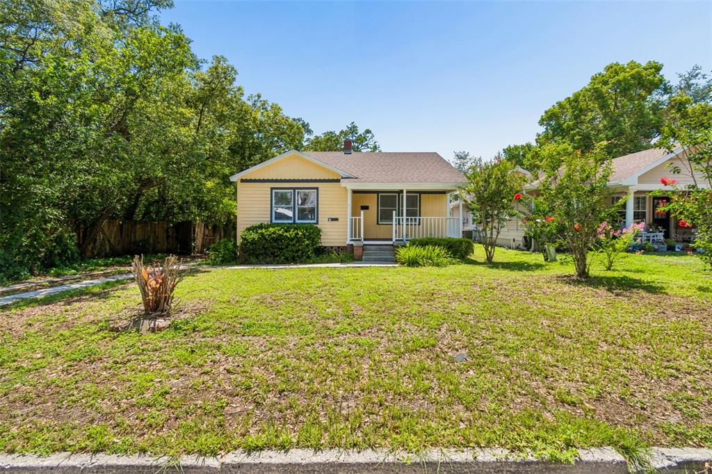 A yellow, single-story house with a front porch sits behind a grassy lawn — 1019 S TENNESSEE AVENUE, LAKELAND, FL
