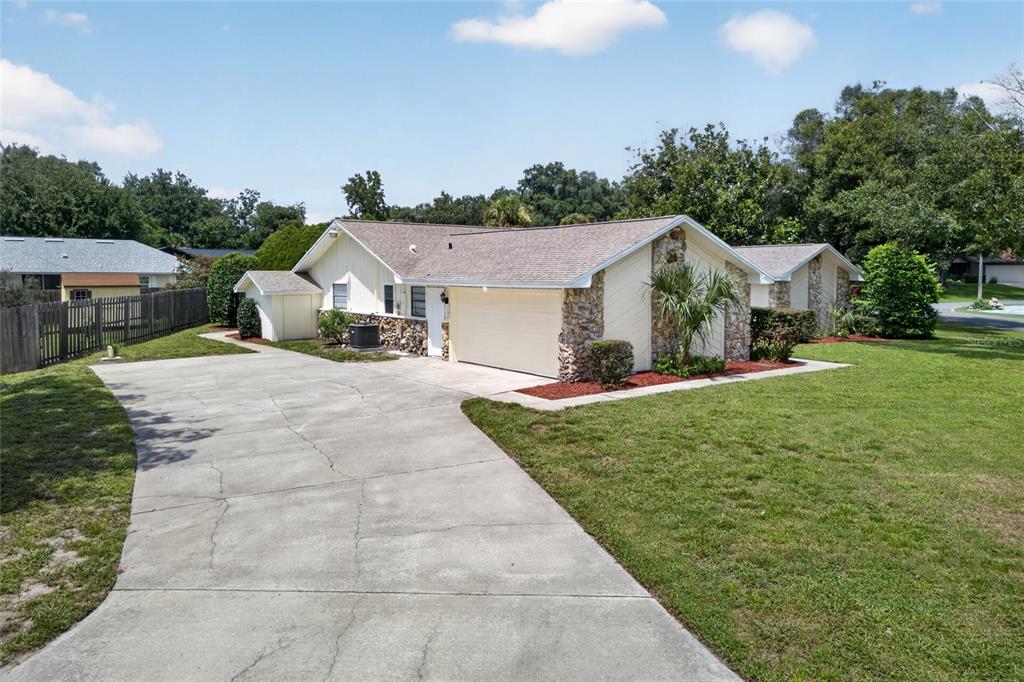 A single-story house with a stone facade, a two-car garage, and a concrete driveway — 2704 BURGOYNE PLACE, DELAND, FL
