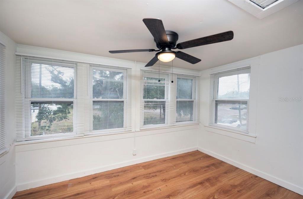 A bedroom with light wood-look flooring, a white wardrobe, a ceiling fan, and two windows — 1701 14TH STREET S UNIT B, ST PETERSBURG, FL