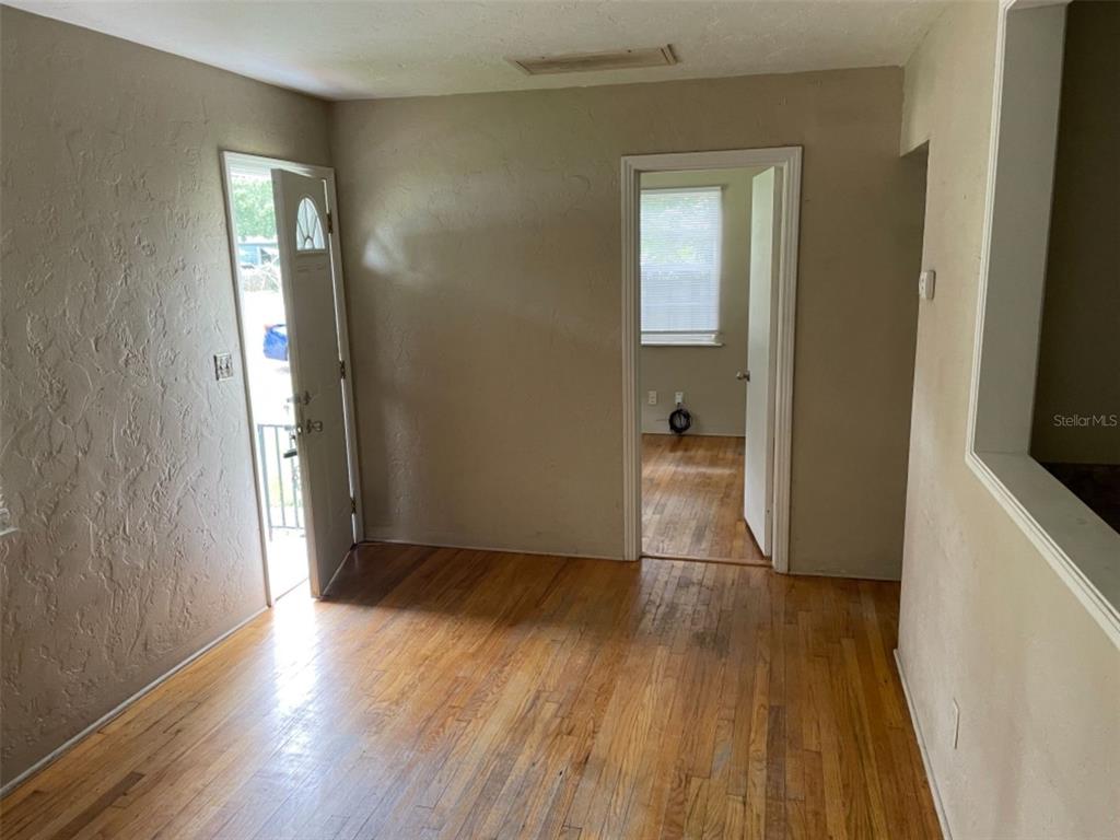 An interior view shows a room with hardwood floors, a front door, and an open doorway — 5013 20TH STREET N, ST PETERSBURG, FL