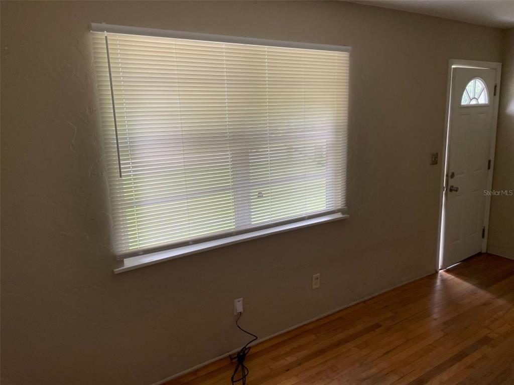 A room with hardwood floors, a large window with white blinds, and a white door — 5013 20TH STREET N, ST PETERSBURG, FL