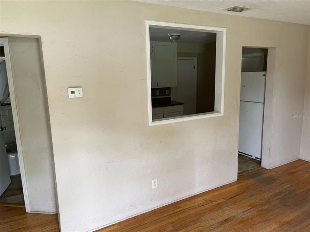 A room with hardwood floors, a wall cutout looking into a kitchen, and two doorways — 5013 20TH STREET N, ST PETERSBURG, FL