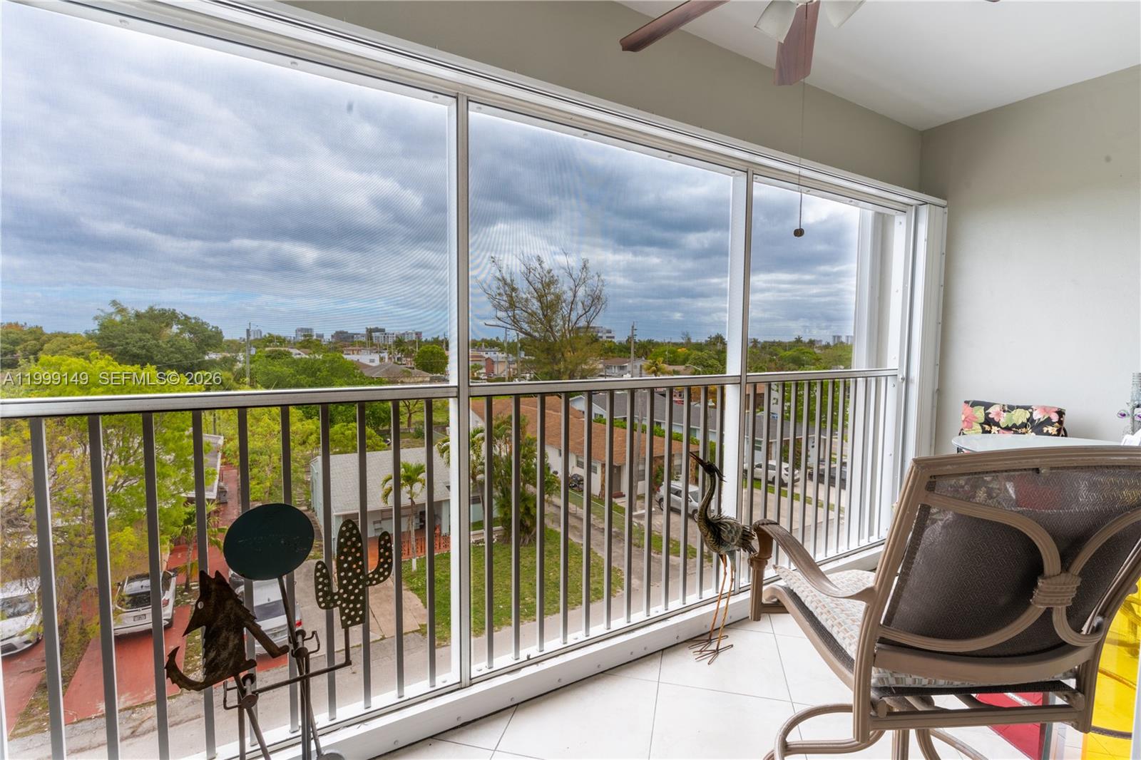 A screened-in balcony features tile flooring, metal railings, and a view of a residential neighborhood — 330 SE 2nd St # 405F, Hallandale Beach FL 33009, HALLANDALE BEACH, FL