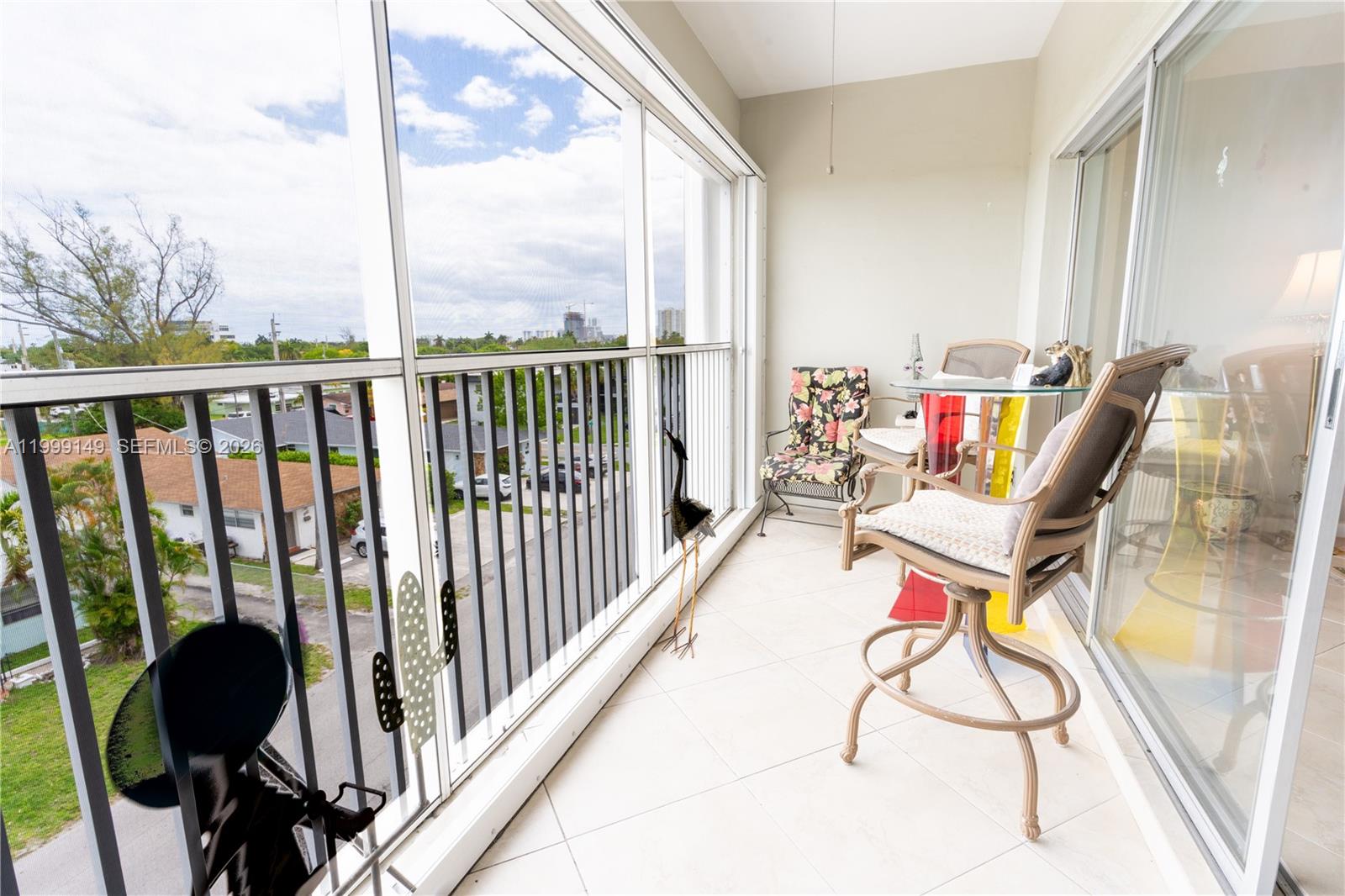 A screened-in balcony features tile flooring, outdoor furniture, and a view of the neighborhood — 330 SE 2nd St # 405F, Hallandale Beach FL 33009, HALLANDALE BEACH, FL