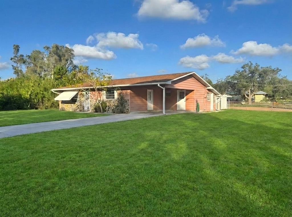 A single-story house with a brown roof, wood siding, and a concrete driveway — 12438 POEM AVENUE, PUNTA GORDA, FL