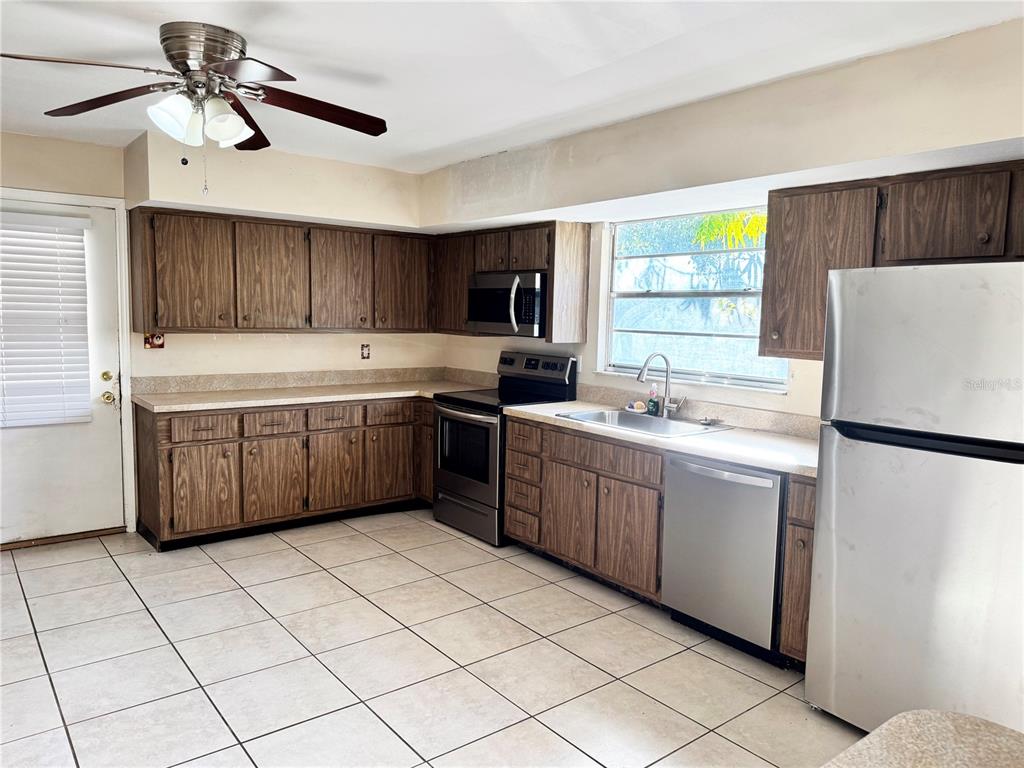 A kitchen features wood-grain cabinets, stainless steel appliances, tile flooring, and a ceiling fan — 12438 POEM AVENUE, PUNTA GORDA, FL