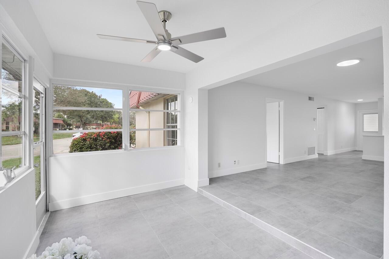 A sunroom with gray tile flooring and a ceiling fan opens into a living area — 737 Nantucket Circle # B, Lake Worth FL 33467, LAKE WORTH, FL