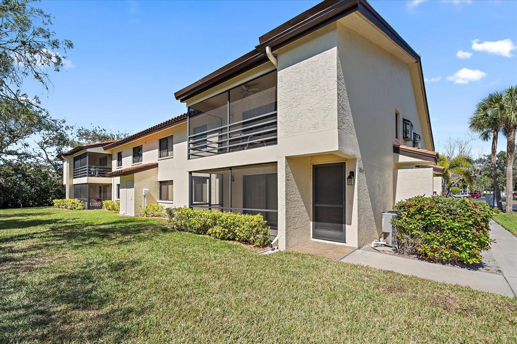 A two-story apartment building with screened balconies and a tan stucco exterior — 5654 GARDENS DRIVE, SARASOTA, FL