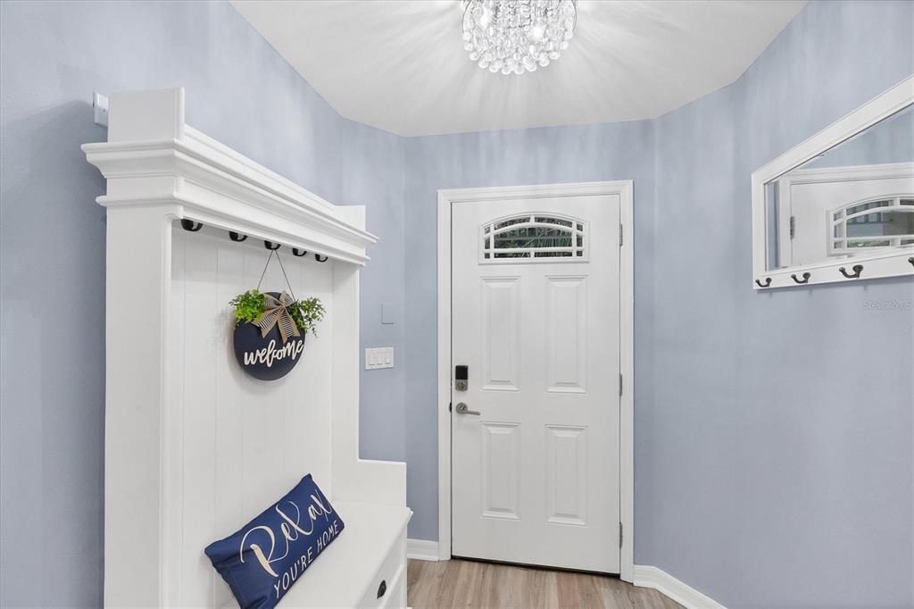 An entryway features light blue walls, a white coat rack bench, and a white door — 3701 54TH DRIVE W UNIT 202, BRADENTON, FL