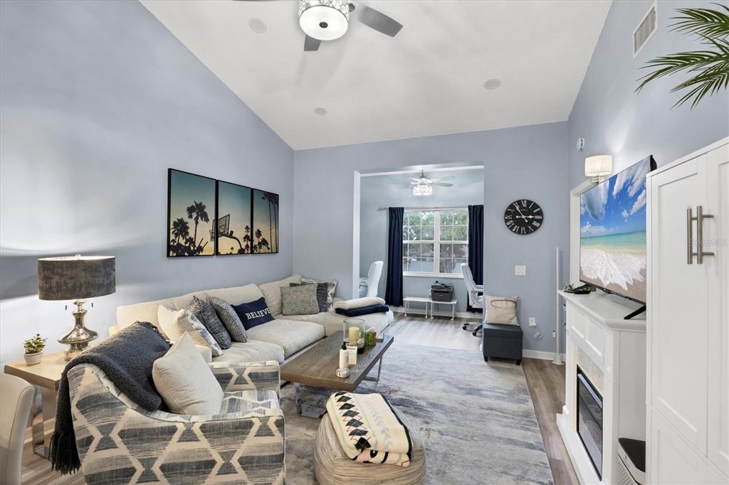 A living room features a sectional sofa, a fireplace with a television, and light-blue walls — 3701 54TH DRIVE W UNIT 202, BRADENTON, FL