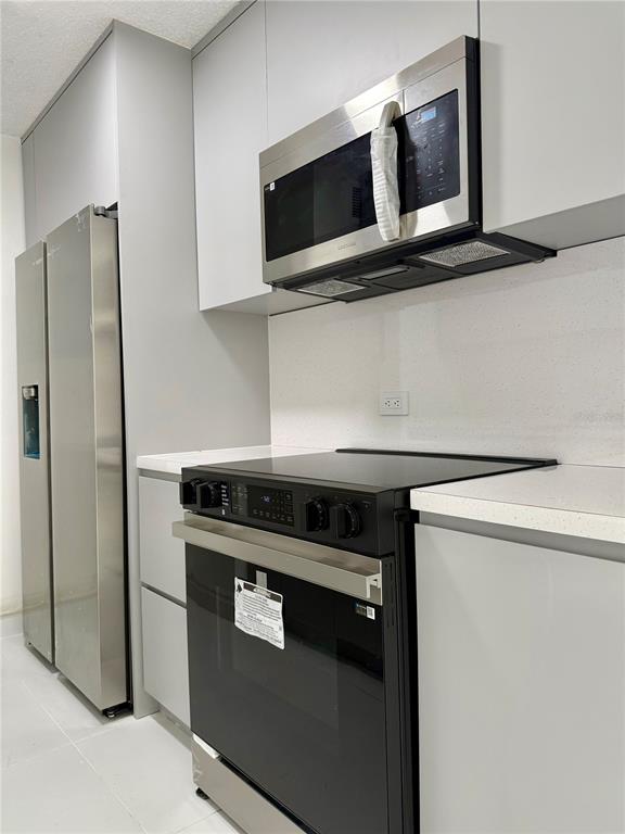 A modern kitchen features stainless steel appliances, light gray cabinetry, and white countertops — 14 AVE.SAN PATRICIO UNIT 1004, GUAYNABO, PR