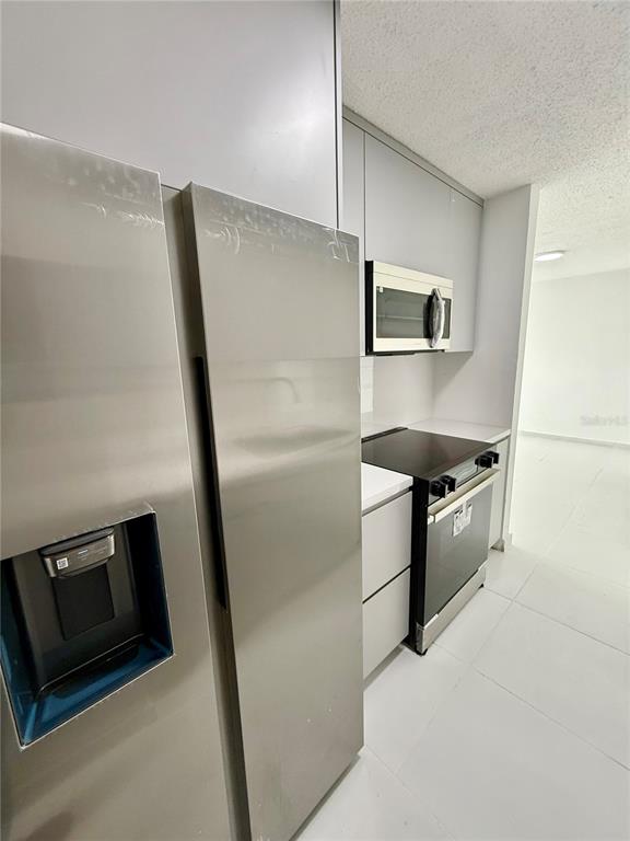 A kitchen features stainless steel appliances, light gray cabinetry, and white tile flooring — 14 AVE.SAN PATRICIO UNIT 1004, GUAYNABO, PR