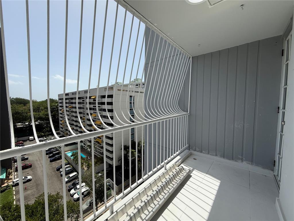 A balcony with white metal railings overlooks a parking lot and a neighboring apartment building — 14 AVE.SAN PATRICIO UNIT 1004, GUAYNABO, PR
