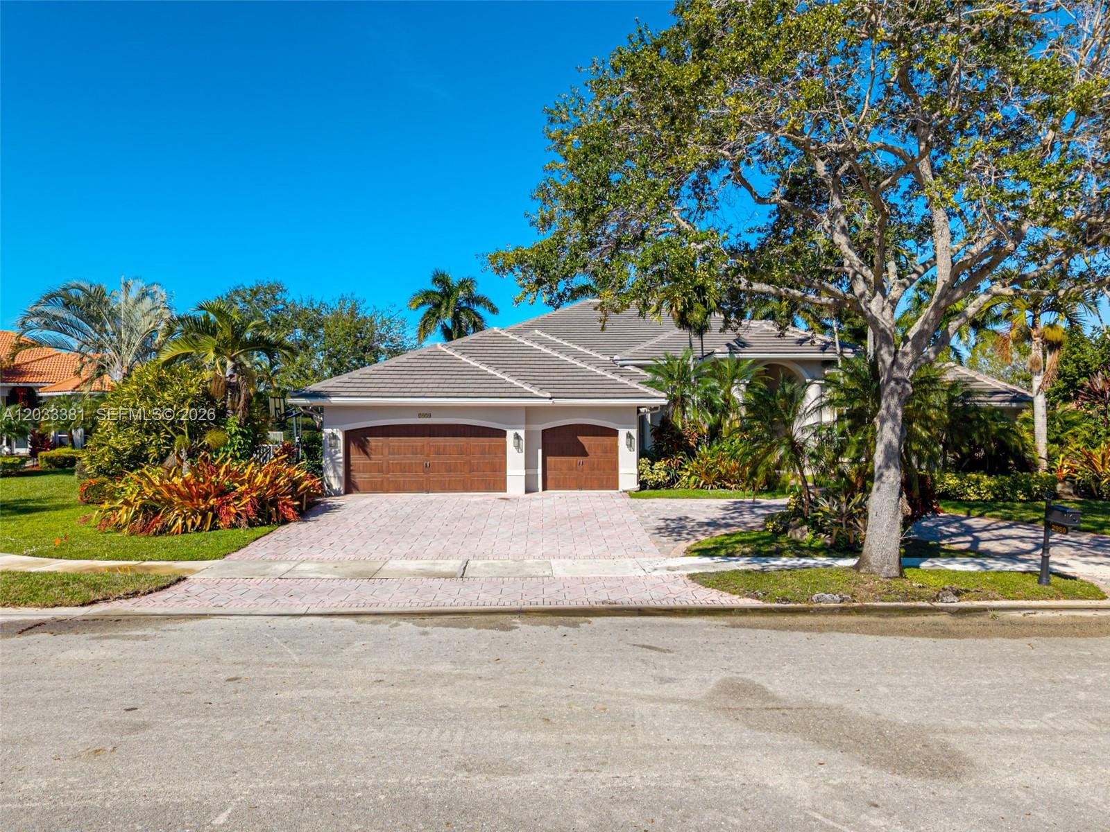 A single-story house with a two-car garage and a paved driveway under a large tree — 2950 Medinah, Weston FL 33332, WESTON, FL