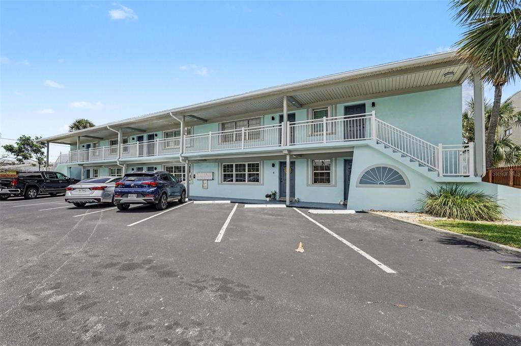 A two-story, light blue apartment building features a parking lot and an exterior staircase — 1011 S MIRAMAR AVENUE UNIT 9, INDIALANTIC, FL