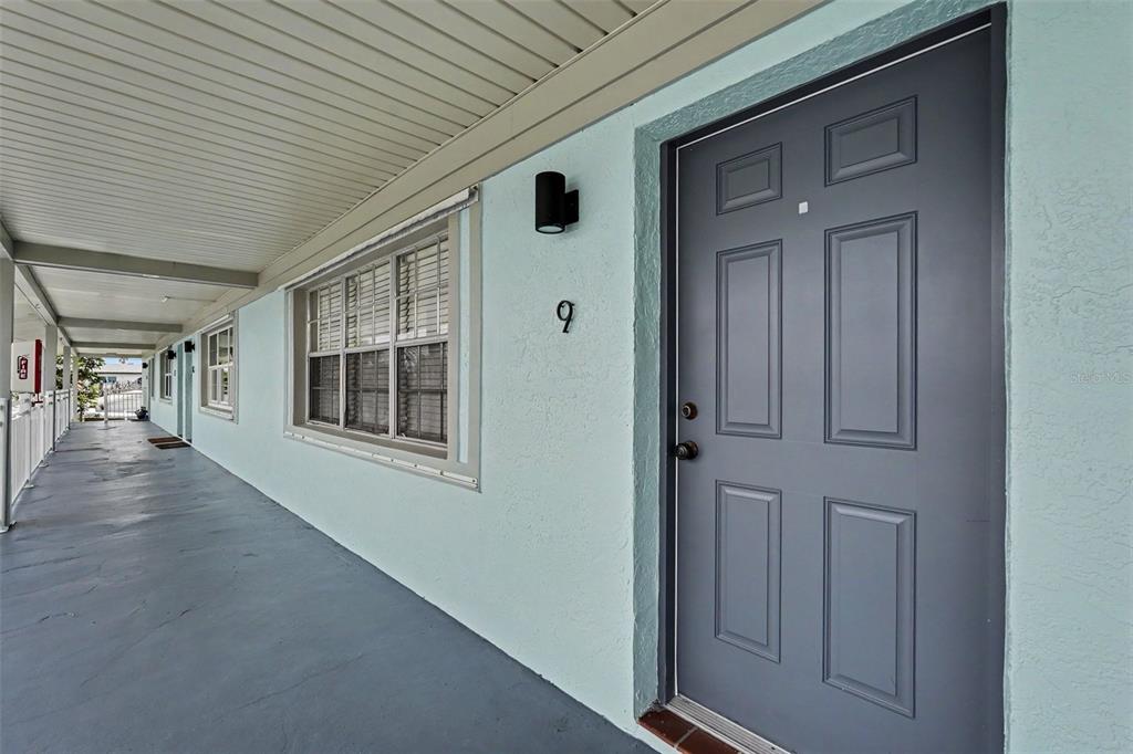 A gray front door with the number nine sits on a covered exterior walkway — 1011 S MIRAMAR AVENUE UNIT 9, INDIALANTIC, FL