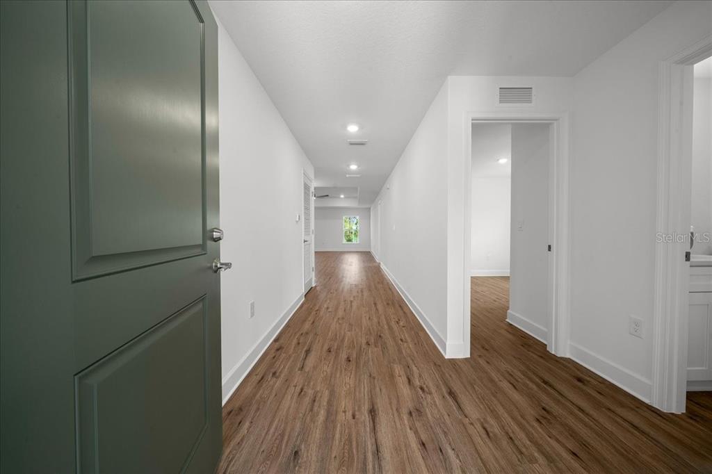 A long hallway with wood-look flooring leads to a room with a window — 6241 FREEPORT DRIVE, SPRING HILL, FL