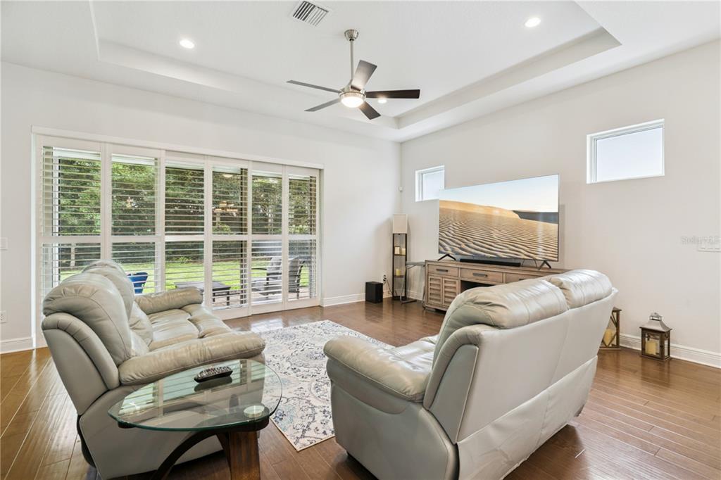 A living room features light gray leather sofas, a glass coffee table, and sliding glass doors — 15709 SHOREBIRD LANE, WINTER GARDEN, FL