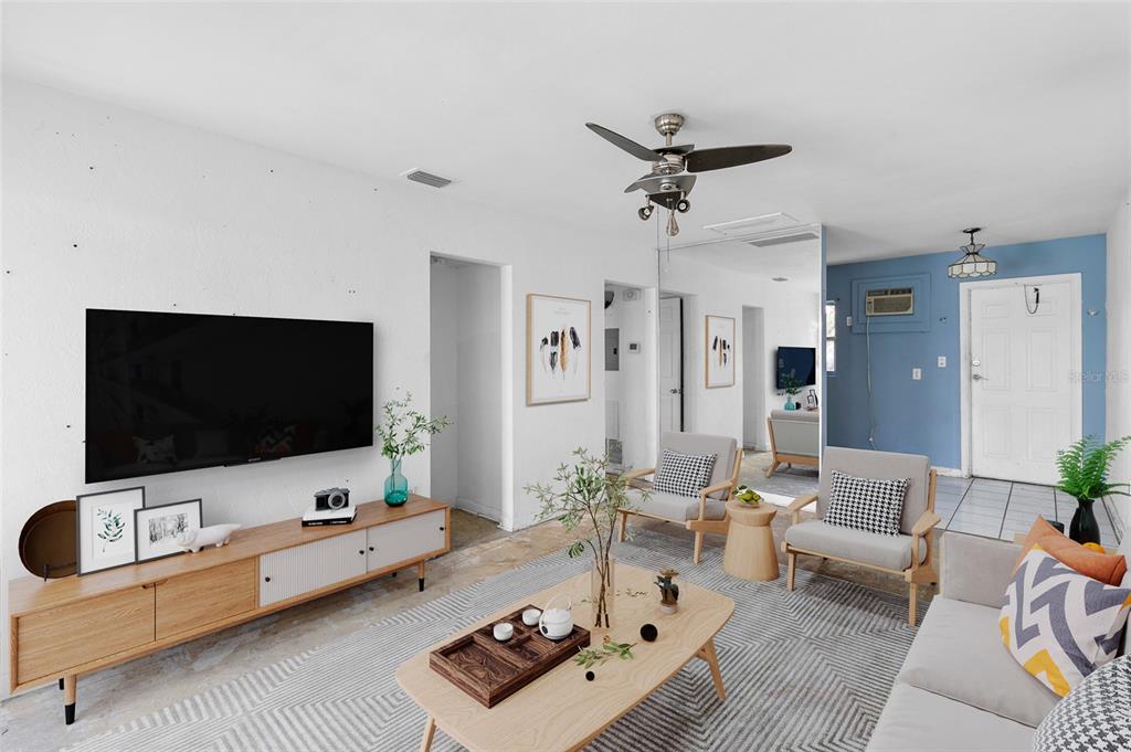 A living room features a wall-mounted television, wooden media console, two armchairs, and a rug — 410 73RD AVENUE, ST PETE BEACH, FL