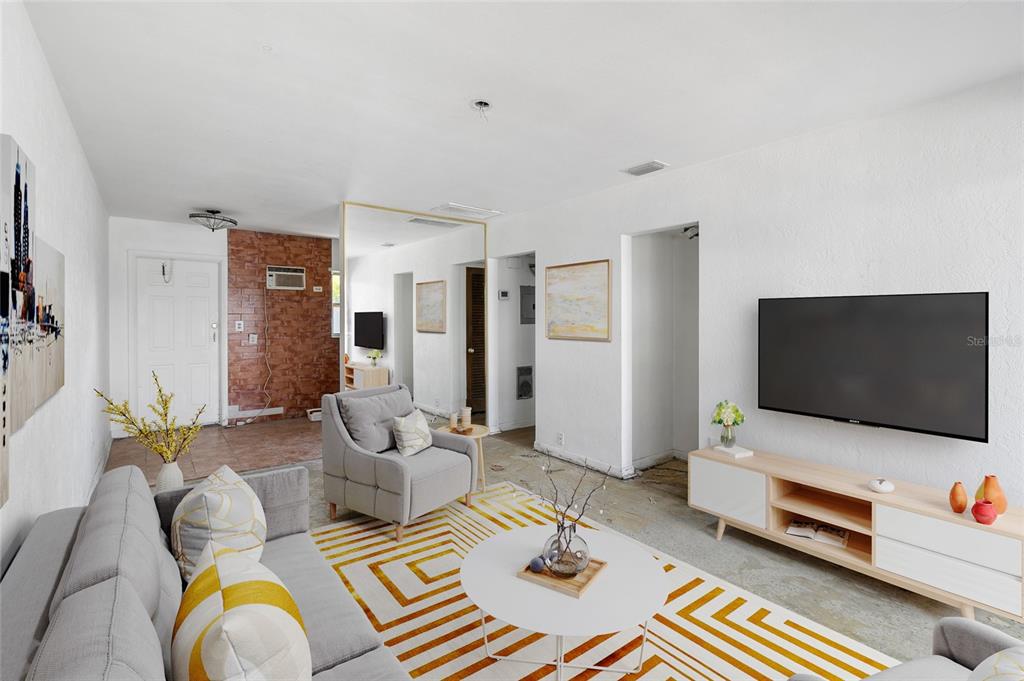 A living room features a gray sofa, a patterned rug, and a wall-mounted television — 410 73RD AVENUE, ST PETE BEACH, FL