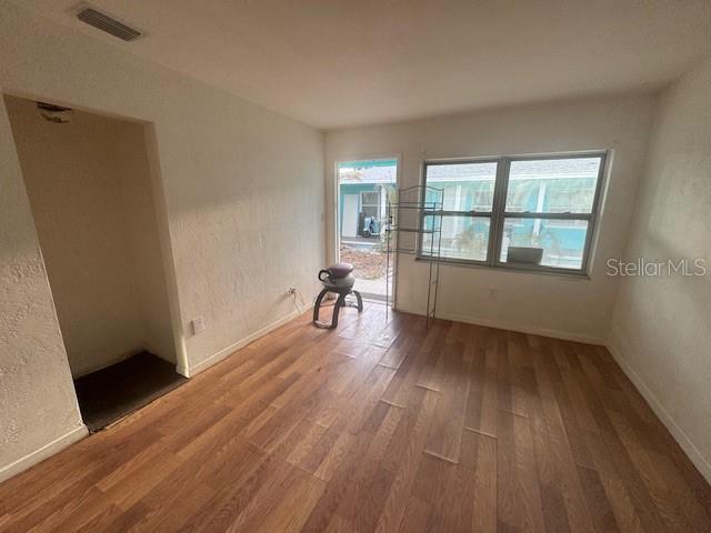 An empty room features wood-look flooring, white walls, a window, and an exterior door — 410 73RD AVENUE, ST PETE BEACH, FL