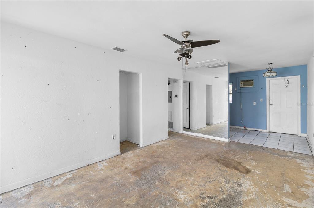 An empty room with white walls, a ceiling fan, mirrored wall, and unfinished concrete flooring — 410 73RD AVENUE, ST PETE BEACH, FL