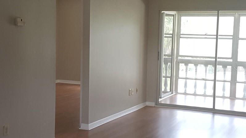 An interior view of a room with light-colored walls, wood-look flooring, and a sliding glass door — 1250 S PINELLAS AVENUE UNIT 809, TARPON SPRINGS, FL