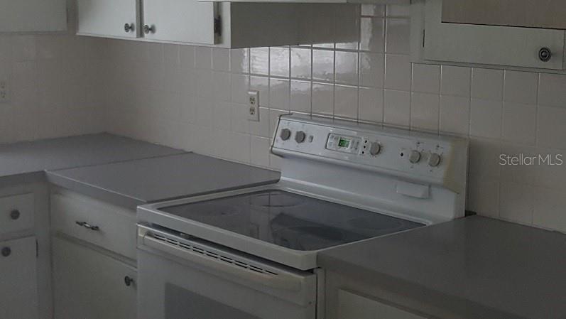 A kitchen features white cabinets, a white electric range, and light gray countertops — 1250 S PINELLAS AVENUE UNIT 809, TARPON SPRINGS, FL