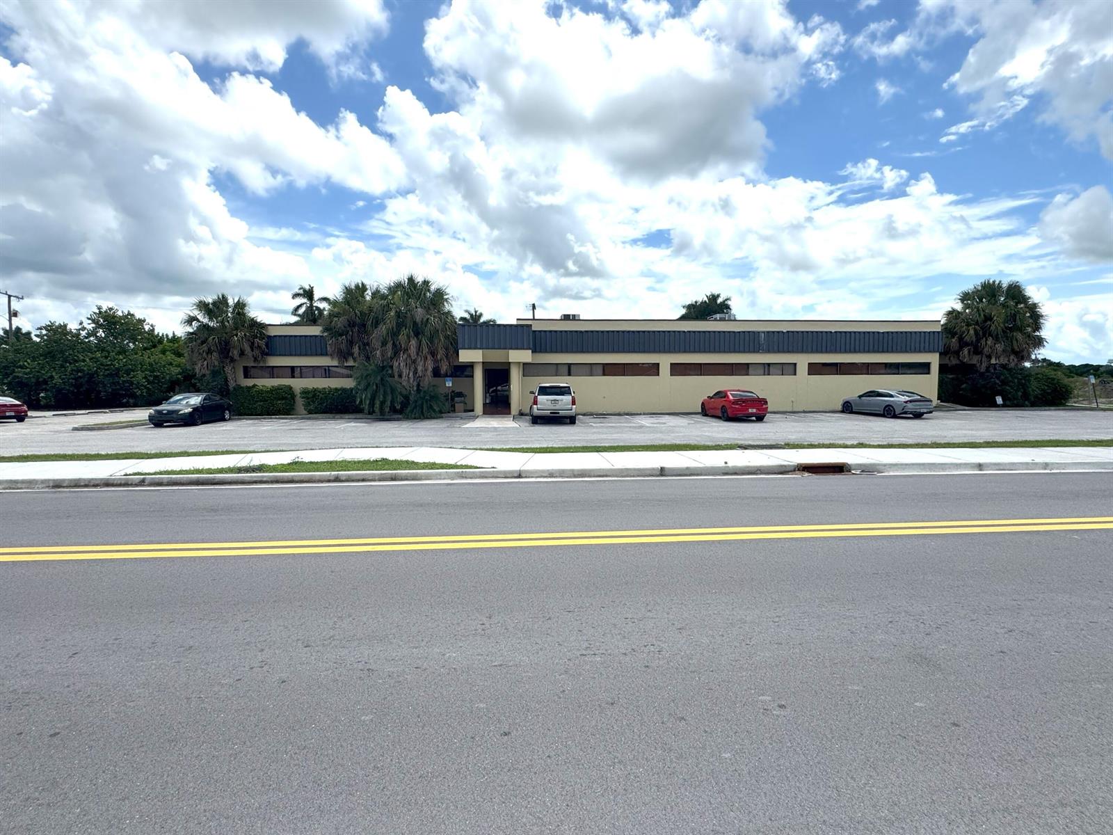 A single-story commercial building with a parking lot sits under a cloudy blue sky — 170 S Barfield Highway, Pahokee FL 33476, PAHOKEE, FL