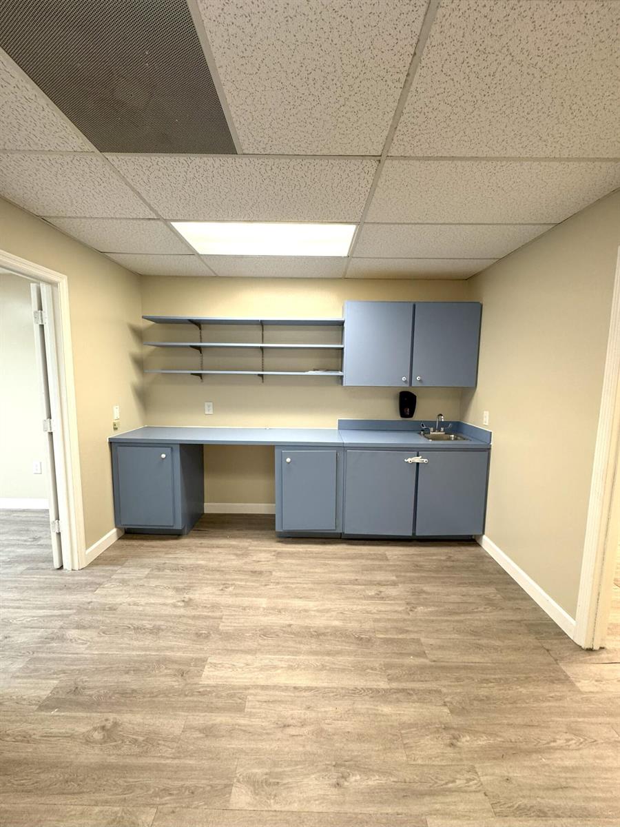 A room with light wood-look flooring, blue cabinets, open shelving, and a small sink — 170 S Barfield Highway, Pahokee FL 33476, PAHOKEE, FL