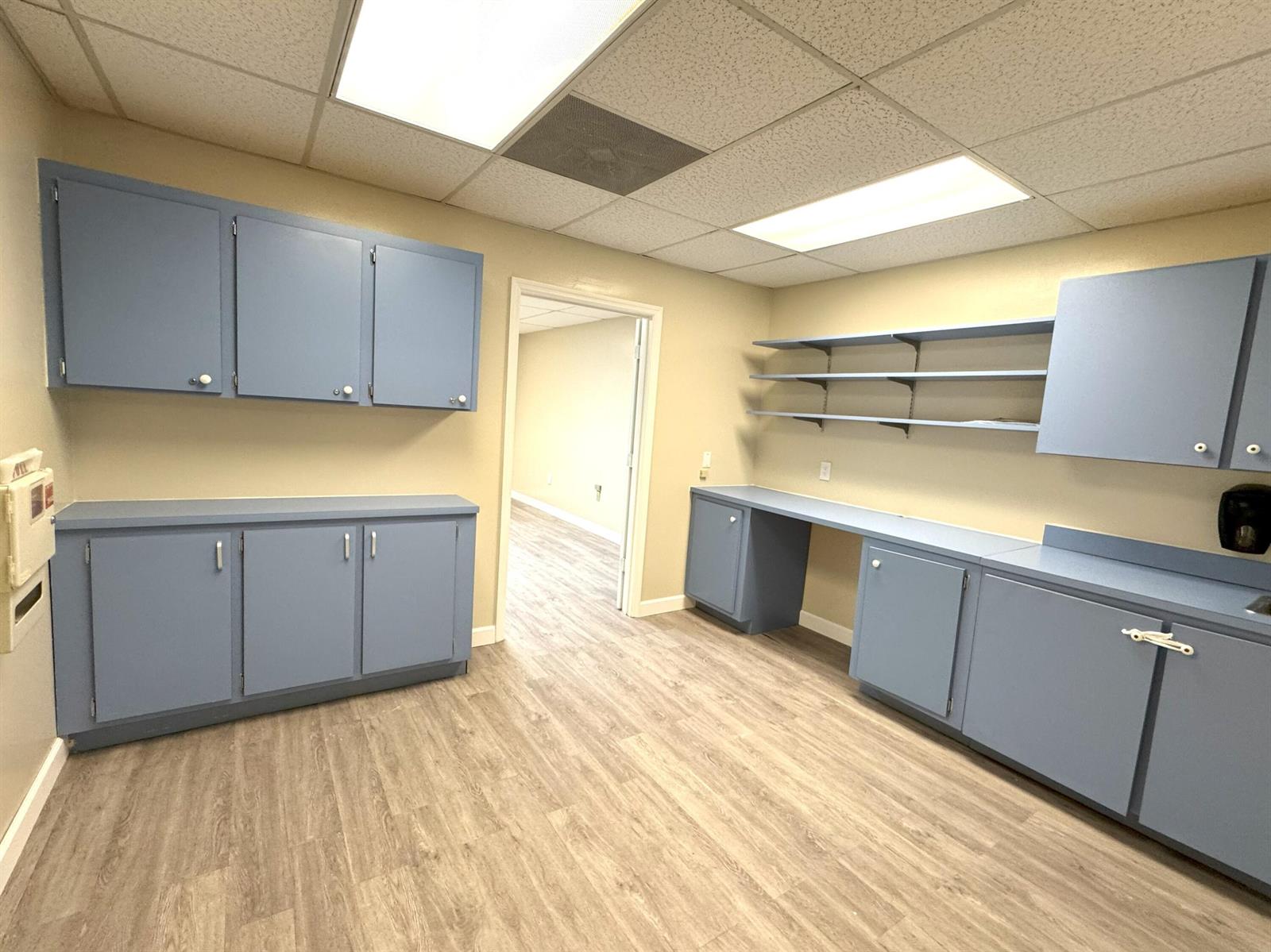 A room with blue cabinets, open shelving, beige walls, and wood-look flooring — 170 S Barfield Highway, Pahokee FL 33476, PAHOKEE, FL