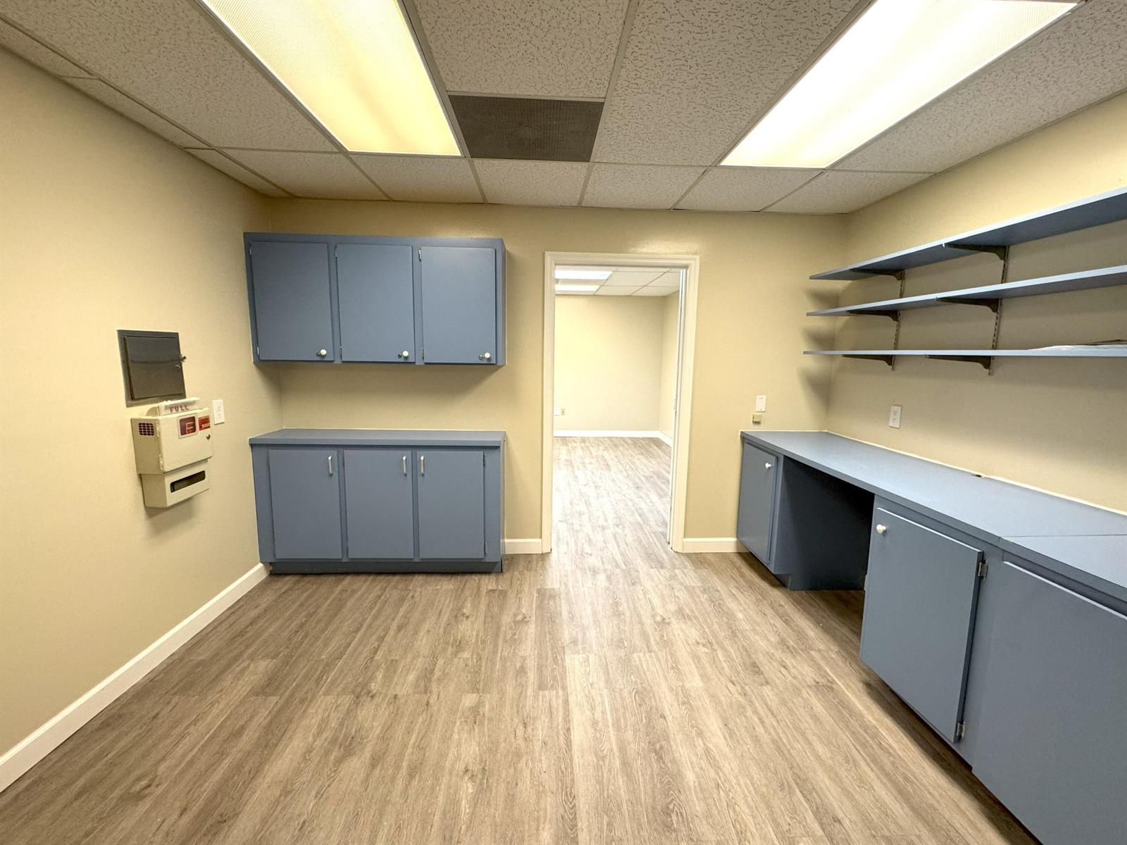 An office or utility room features blue cabinetry, open shelving, and light wood-look flooring — 170 S Barfield Highway, Pahokee FL 33476, PAHOKEE, FL