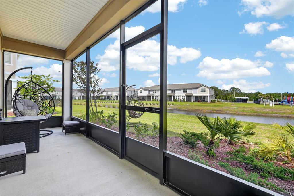 A screened-in patio overlooks a grassy lawn, a small canal, and neighboring residential buildings — 336 REDBUD ROAD, PALM COAST, FL