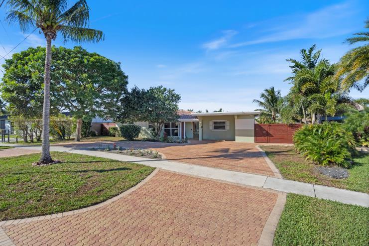 A single-story house with a paved driveway and palm trees under a clear blue sky — 1001 SE 5 Avenue, Pompano Beach FL 33060, POMPANO BEACH, FL