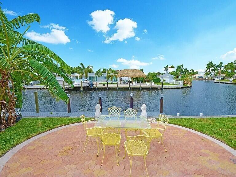 A yellow patio dining set sits on a paved terrace overlooking a canal — 1001 SE 5 Avenue, Pompano Beach FL 33060, POMPANO BEACH, FL