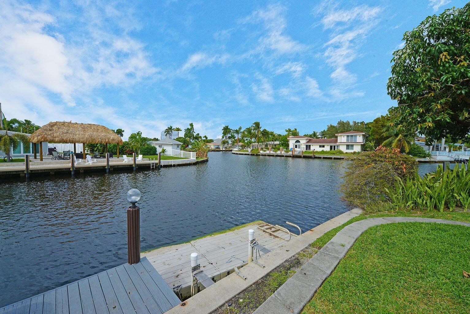 A wooden dock overlooks a canal with a tiki hut and houses in the background — 1001 SE 5 Avenue, Pompano Beach FL 33060, POMPANO BEACH, FL