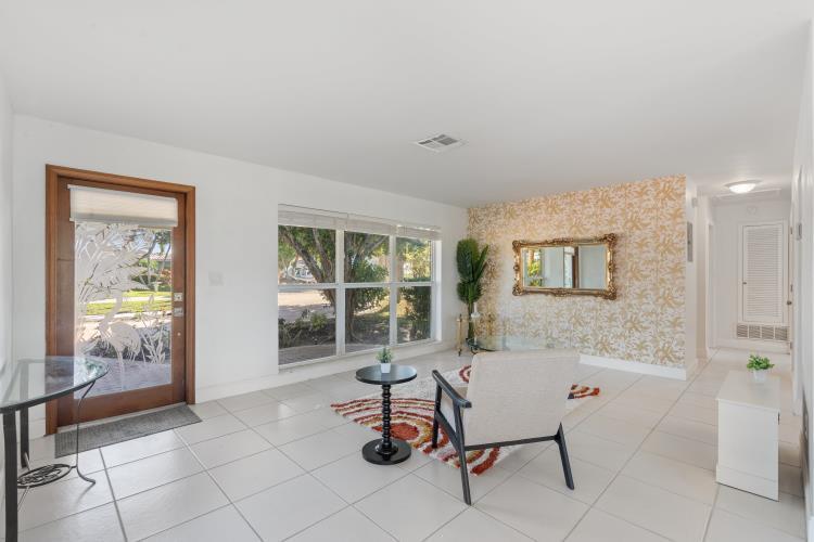 A bright living room features white tile floors, a patterned accent wall, and a glass door — 1001 SE 5 Avenue, Pompano Beach FL 33060, POMPANO BEACH, FL