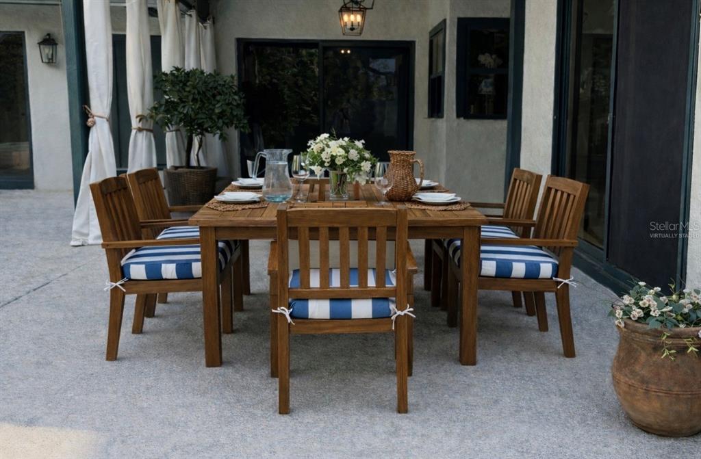 A wooden dining set with blue and white striped cushions sits on a covered patio — 9115 BAY SIDE COURT, ORLANDO, FL