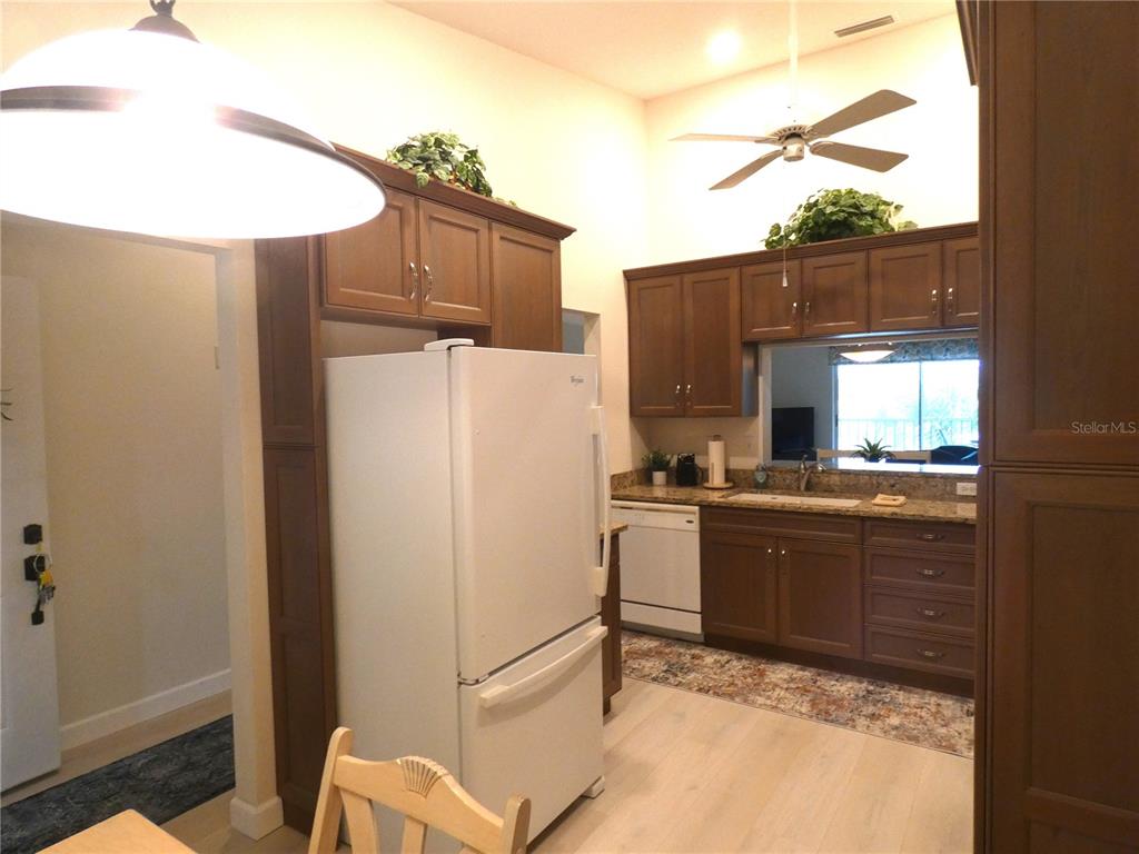 A kitchen with wood cabinets, a white refrigerator, and light-colored flooring under a ceiling fan — 9300 CLUBSIDE CIRCLE UNIT 1307, SARASOTA, FL