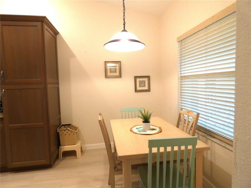A dining area features a light wood table, teal chairs, and a tall brown cabinet — 9300 CLUBSIDE CIRCLE UNIT 1307, SARASOTA, FL