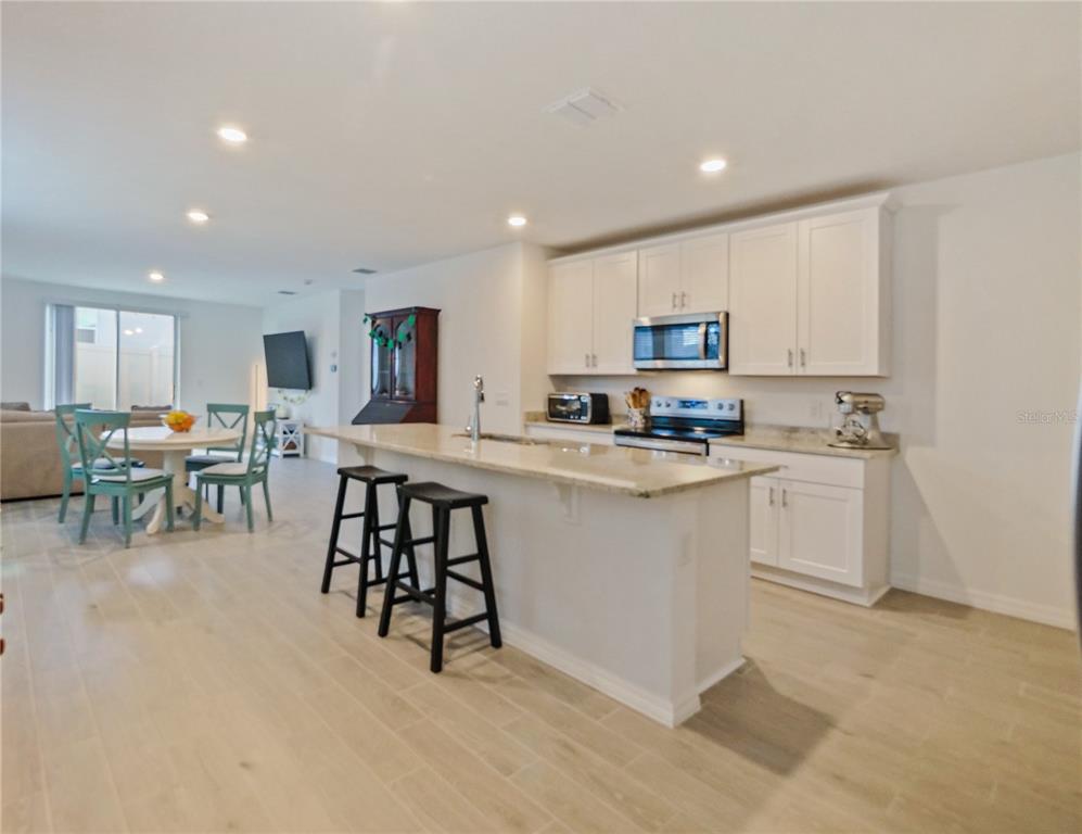 A kitchen with white cabinets, granite countertops, and a breakfast bar with two black stools — 4847 RIGGING ST, HAINES CITY, FL