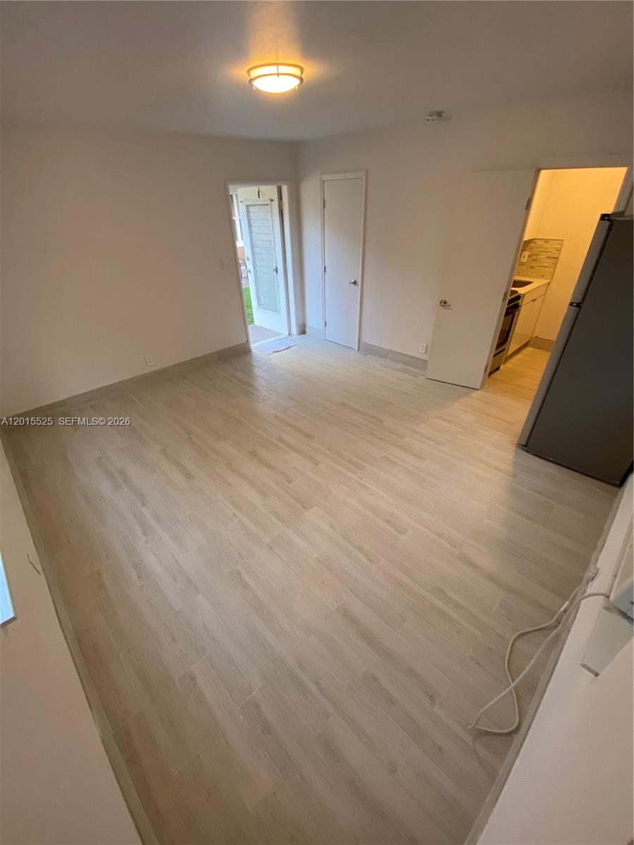 This room features light-colored wood-look flooring, a ceiling light, and access to a kitchen — 1723 Liberty St # 6, Hollywood FL 33020, HOLLYWOOD, FL