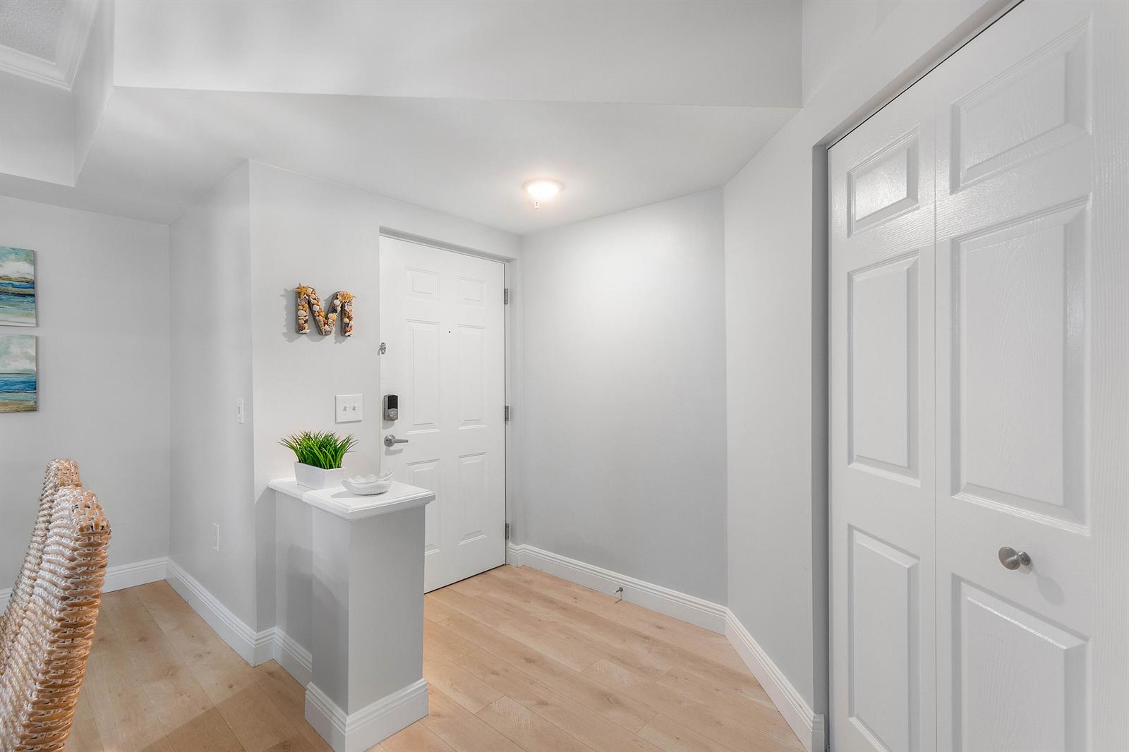 An entryway features light wood flooring, a white front door, and a small half-wall console — 2408 Tuscany Way # 2408, Boynton Beach FL 33435, BOYNTON BEACH, FL