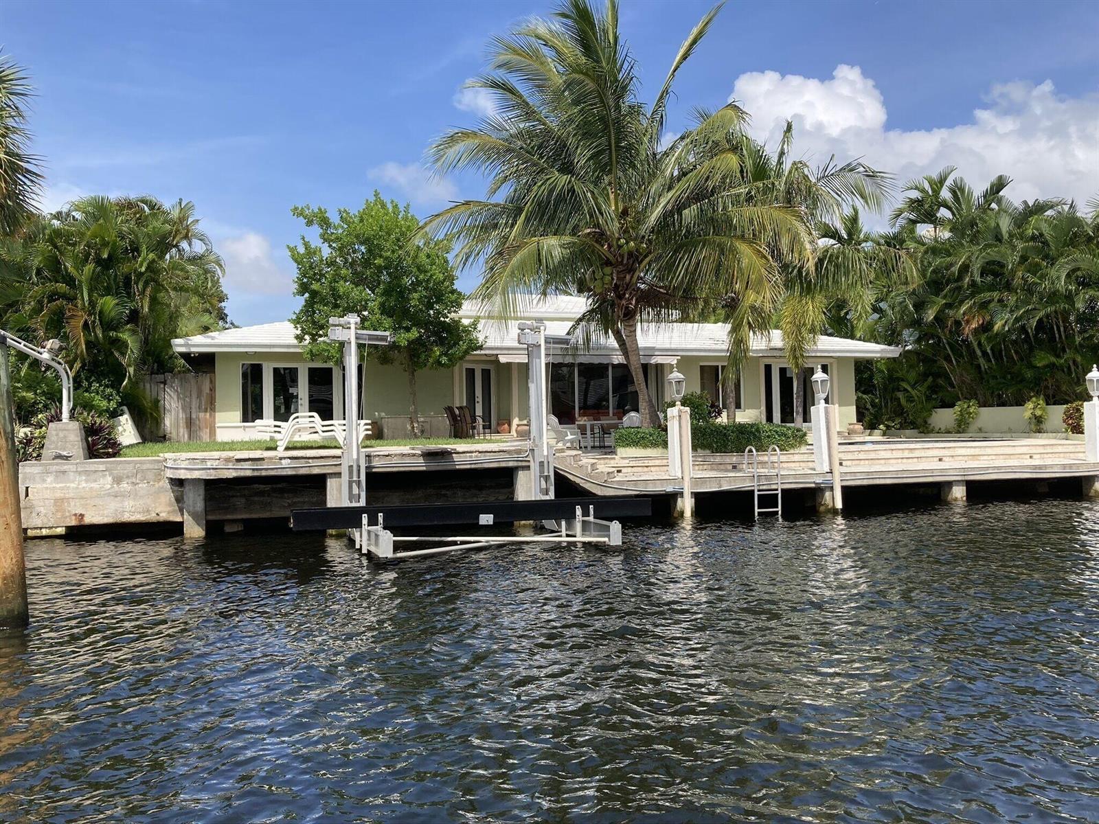 A waterfront house with a boat lift, palm trees, and a concrete dock — 2740 NE 10th Street, Pompano Beach FL 33062, POMPANO BEACH, FL