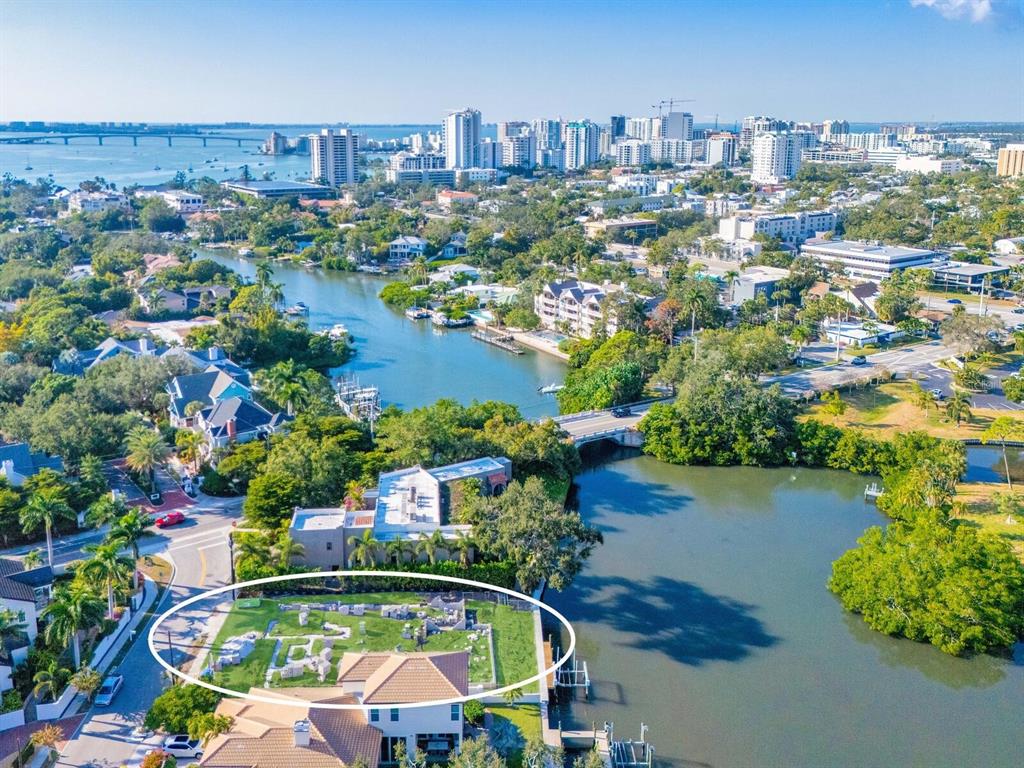 An aerial view shows a waterfront property with a fenced yard containing stone ruins — 1821 LINCOLN DRIVE, SARASOTA, FL